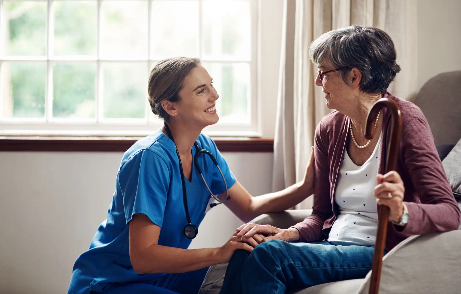 A caregiver speaking warmly with an older adult during a home visit.