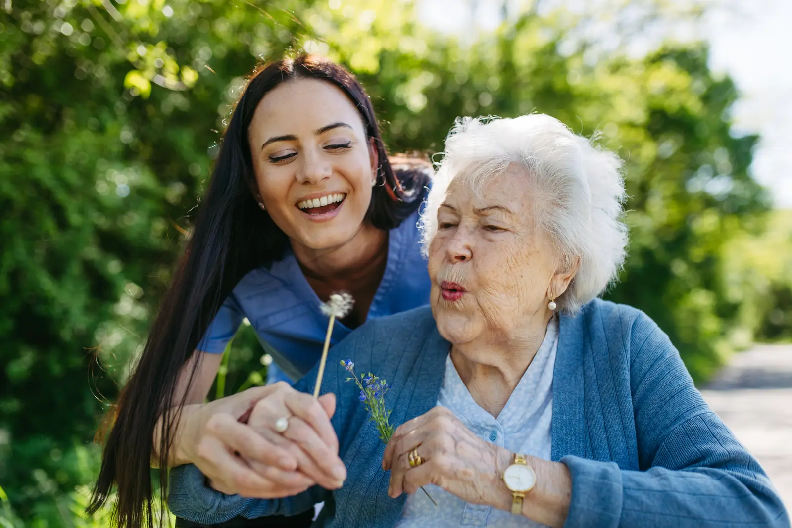 A caregiver sharing a light outdoor moment with an older adult.