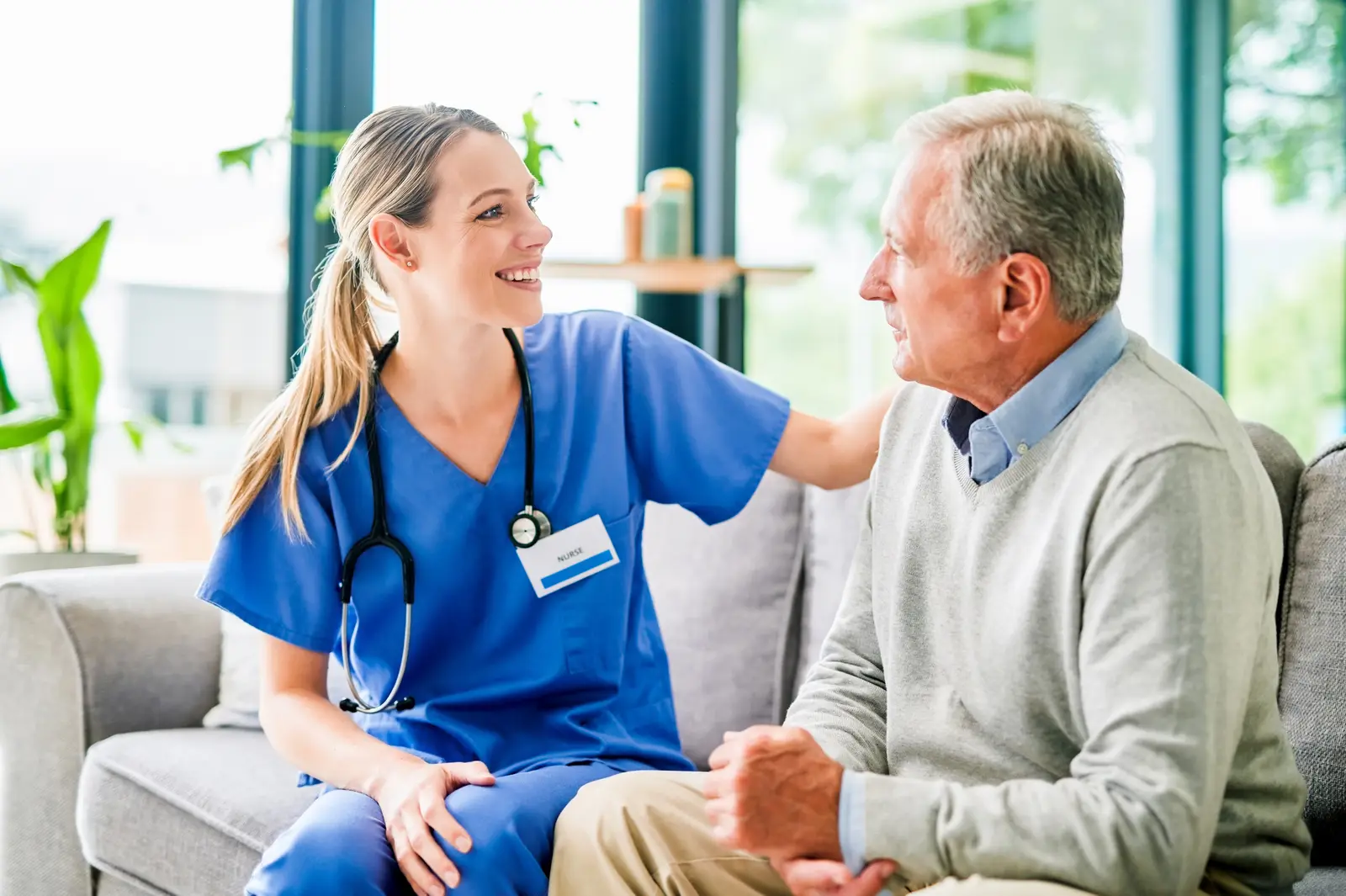 A caregiver speaking with an older adult man during a home visit.